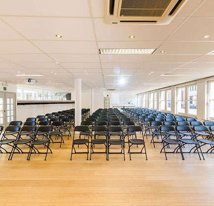 large conference hall with dozens rows of dark chairs