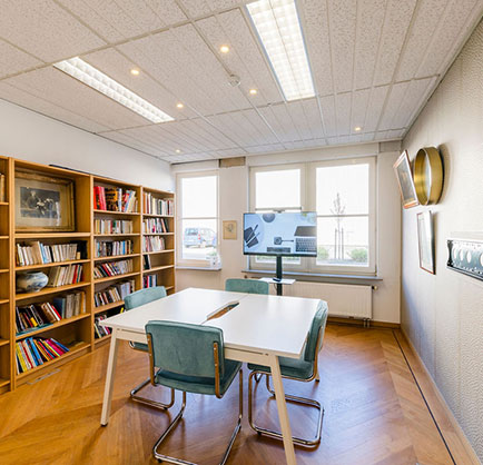 table with four chairs by a library and a TV