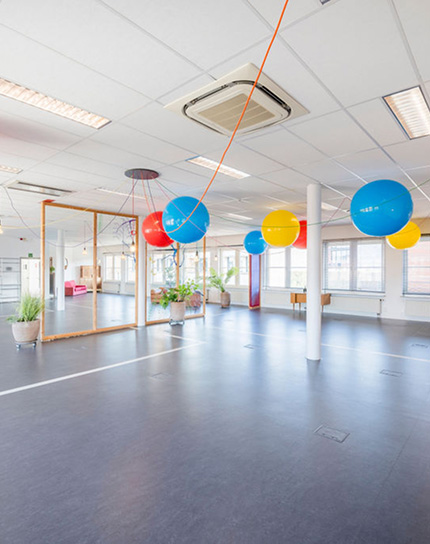 Spacious room with colorful balloons, plants, and glass meeting cube